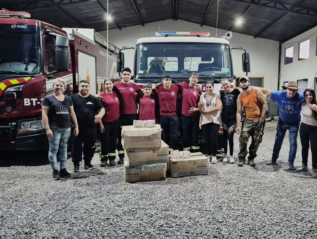 Bomberos y vecinos en la sala de máquinas junto a una donación de mascarillas